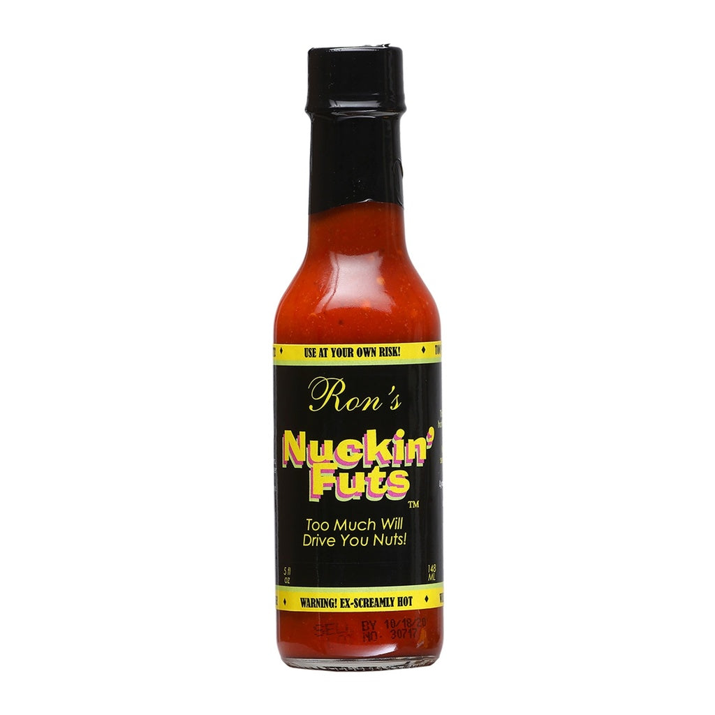 Glass bottle of Nuckin’ Futs Hot Sauce with black label, yellow warning bands, and red sauce inside; labeled 5 fl oz and marked extremely hot.
