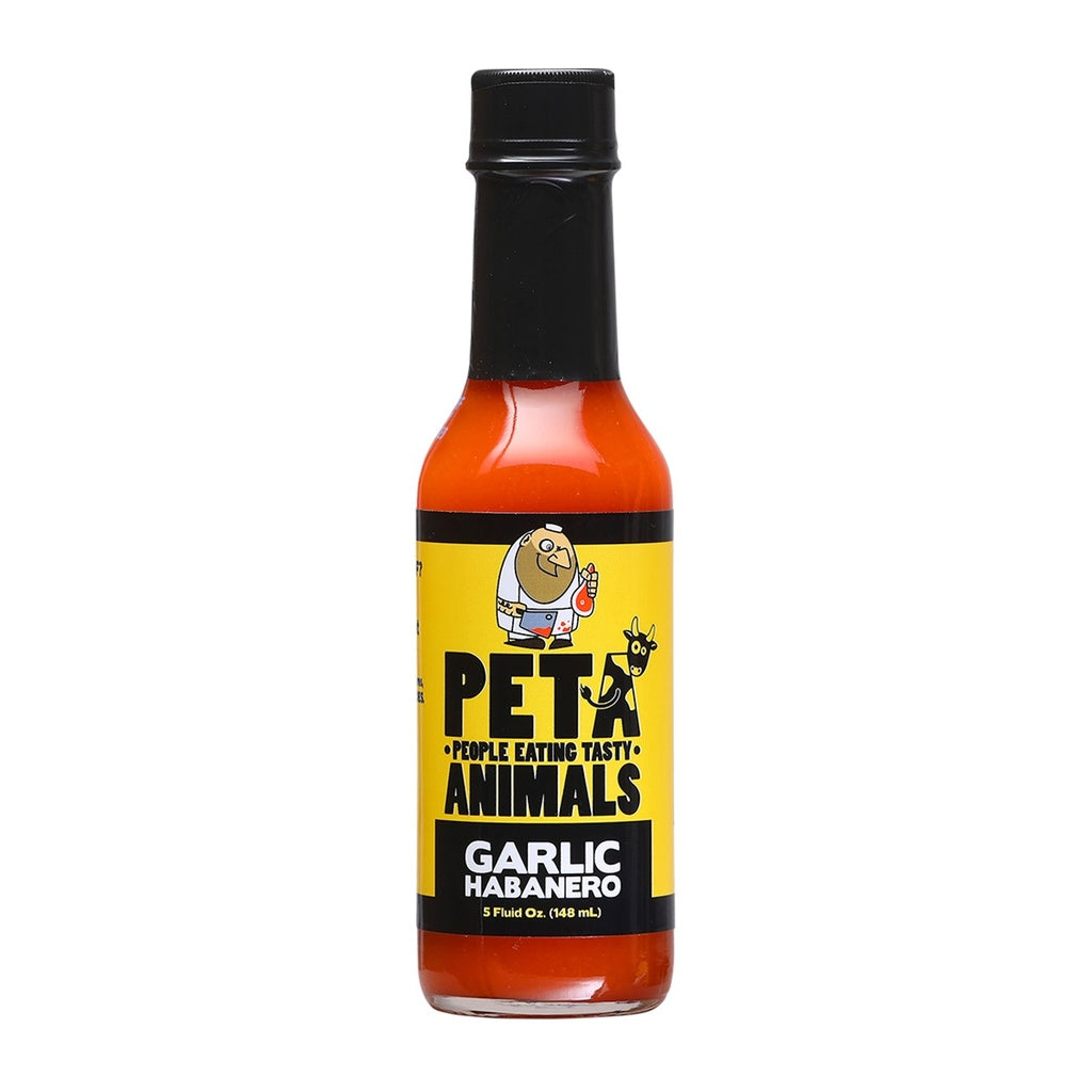 A 5-ounce bottle of PETA Garlic Habanero Hot Sauce with a black cap and bright orange-red sauce inside. The yellow label features a cartoon butcher holding a cleaver alongside a cow, with bold text reading āPETA ā People Eating Tasty Animalsā and āGarlic Habanero.ā