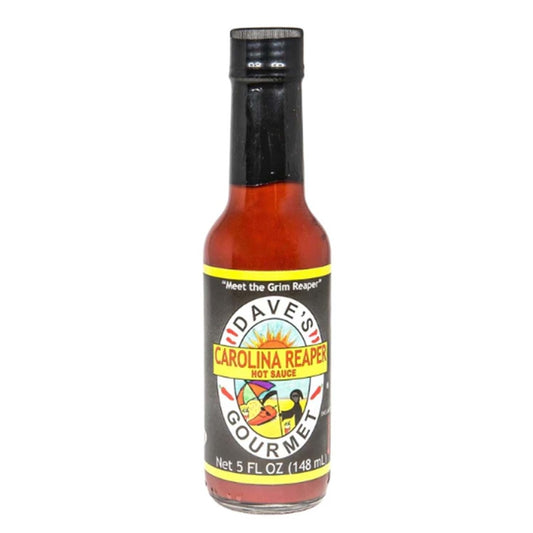 A 5-ounce bottle of Dave’s Gourmet Carolina Reaper Hot Sauce with a black cap and black label featuring the Dave’s Gourmet sun logo. The label displays “Carolina Reaper Hot Sauce” and shows red-orange sauce inside the bottle. The bottom of the label reads “Net Wt. 5 fl oz (148 mL).” UPC: 753469000905