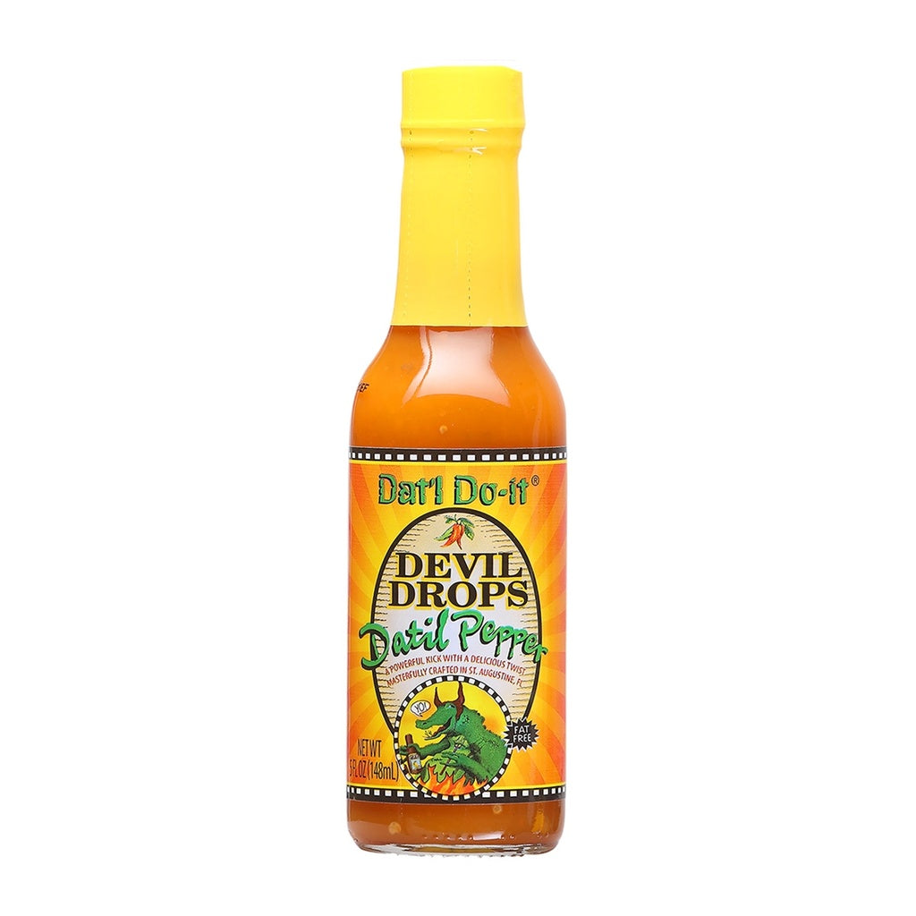 A bottle of Dat'l Do-It Devil Drops Hot Sauce filled with bright orange sauce. The bottle has a yellow cap and a yellow-and-orange label with a sunburst background. The label reads “Dat’l Do-It Devil Drops Datil Pepper” and features a cartoon green alligator breathing fire. The bottle is 5 ounces.