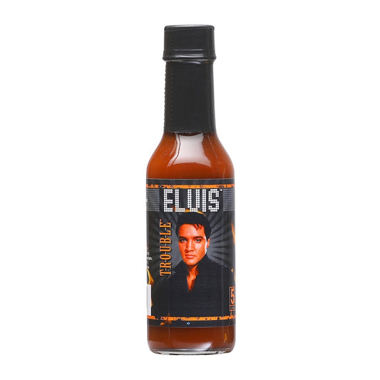 A 5 fl oz bottle of Elvis T-R-O-U-B-L-E Hot Sauce with a dark label featuring Elvis Presley facing forward; the bottle contains a reddish-brown, smoky sauce. UPC: 870128018511.