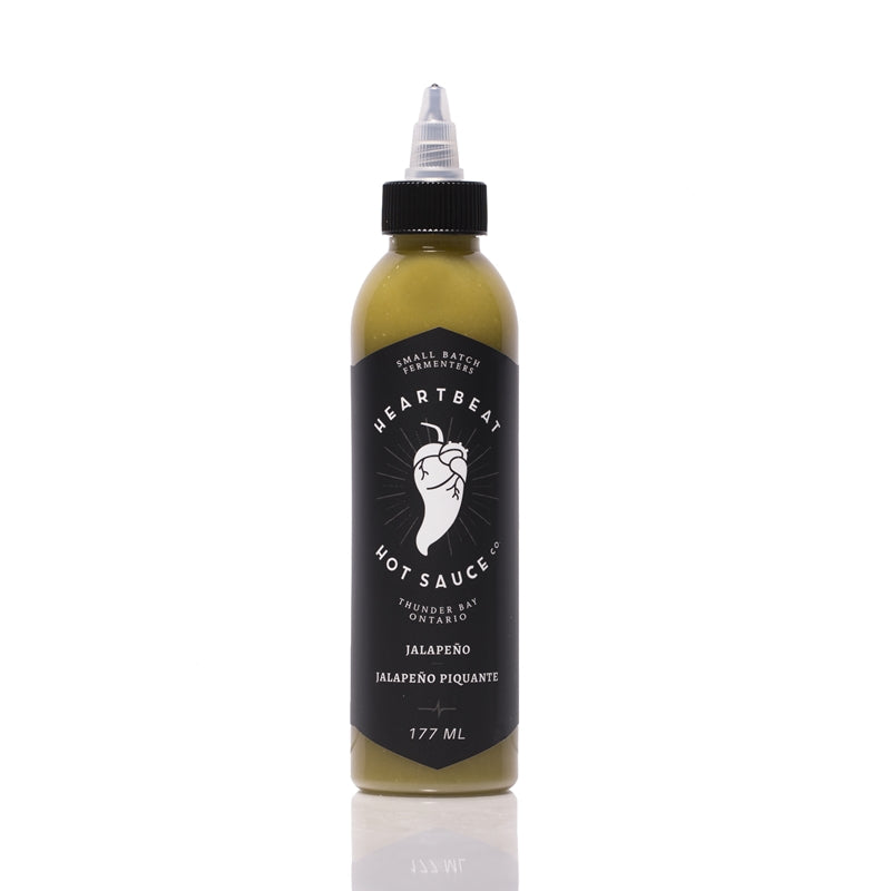 Tall squeeze bottle of Heartbeat Jalapeño Hot Sauce with a black label featuring a white pepper-heart logo; green sauce visible inside; labeled “Jalapeño” with 177 mL noted at the bottom.
