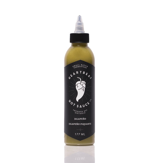 Tall squeeze bottle of Heartbeat Jalapeño Hot Sauce with a black label featuring a white pepper-heart logo; green sauce visible inside; labeled “Jalapeño” with 177 mL noted at the bottom.