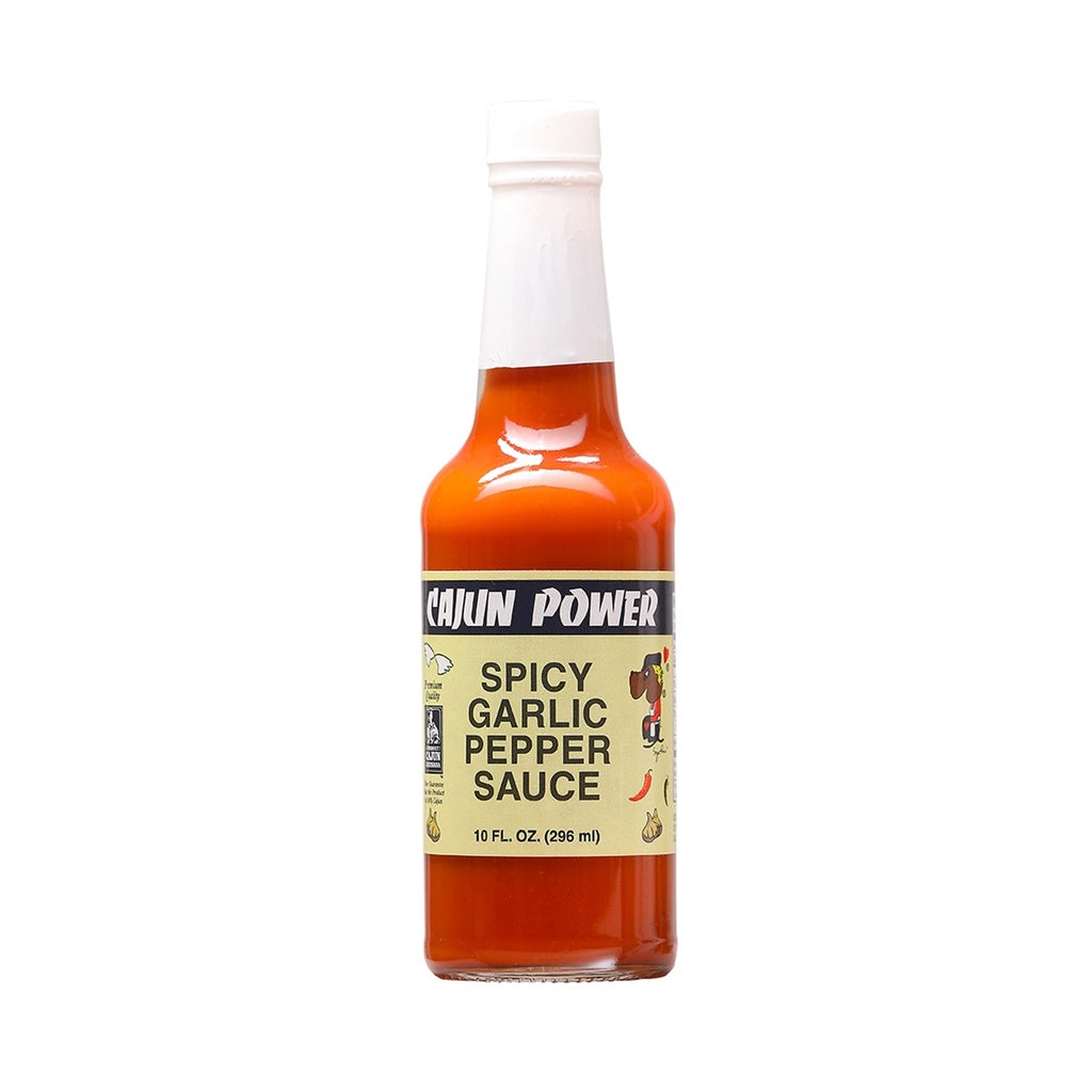 A bottle of Cajun Power Spicy Garlic Pepper Sauce filled with bright orange-red sauce. The label is light yellow with black text reading “Spicy Garlic Pepper Sauce,” and shows small illustrations of garlic, peppers, and a cartoon cook. The bottle has a white cap and contains 10 fl oz (296 ml).
