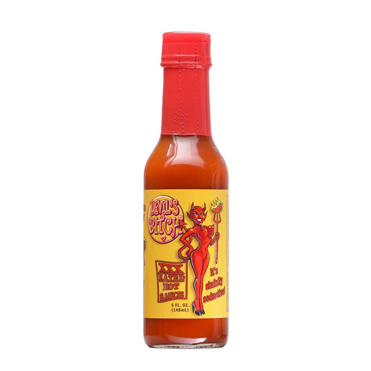 A 5 fl oz bottle of Devil’s Bitch XXX Rated Hot Sauce. The sauce is a deep red-orange color and the bottle is topped with a bright red wax-style seal. The yellow label features a cartoon devil woman holding a fiery pitchfork, with bold text reading “Devil’s Bitch” and “XXX Rated Hot Sauce.” Additional text on the label says “It’s Sinfully Seductive!”