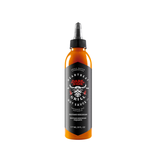 Tall squeeze bottle of Heartbeat Darkside of the Grill Shiitake Szechuan Hot Sauce with black label, stormtrooper-style grill graphic, and orange sauce visible; labeled 6 fl oz / 177 mL.