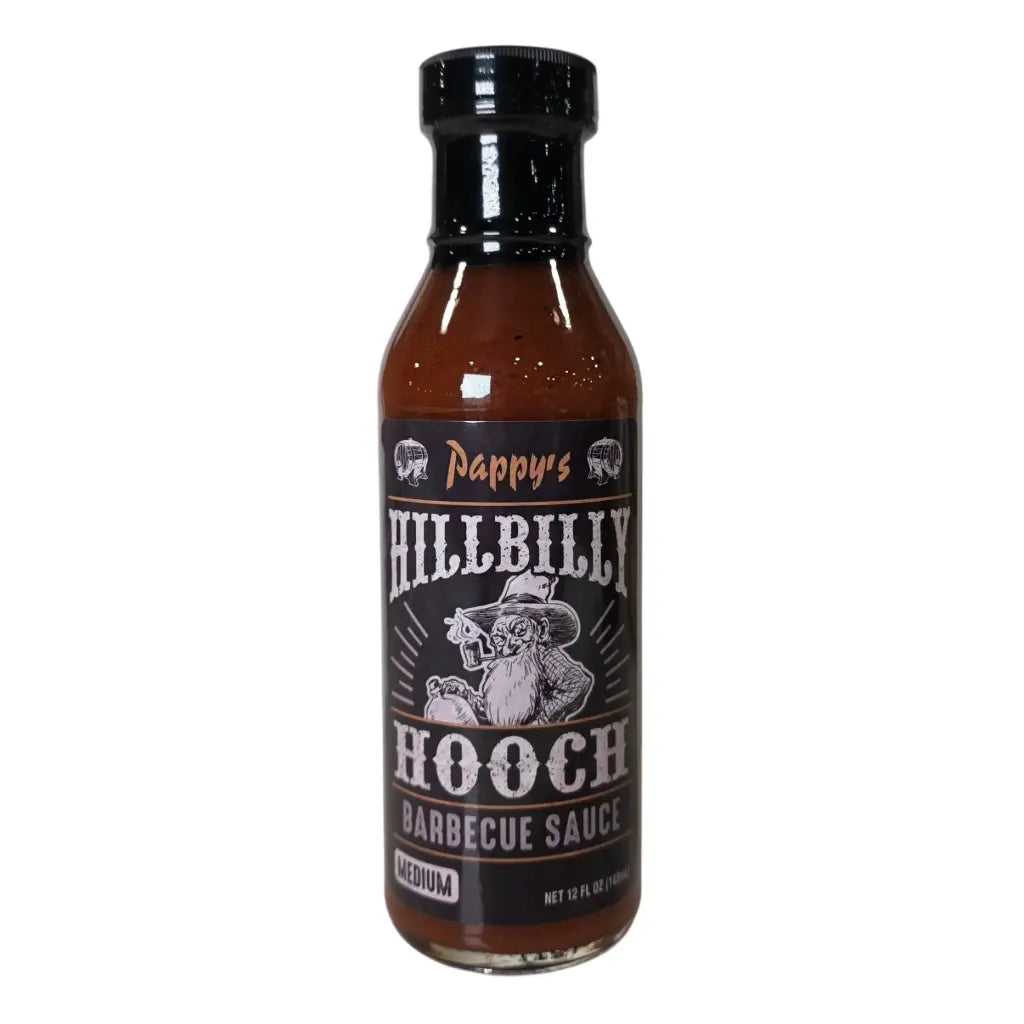 A bottle of Pappy’s Hillbilly Hooch Barbecue Sauce (Medium). The sauce is dark brown and comes in a 12 fl oz bottle with a black cap. The label is black with bold white lettering and features a cartoon hillbilly character holding a jug, accented with rustic design elements.