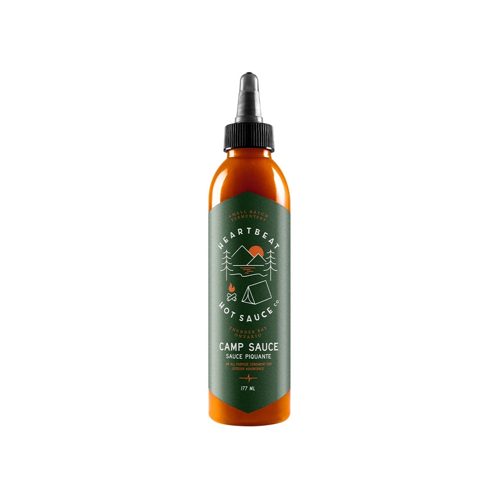 Tall squeeze bottle of Heartbeat Camp Sauce with green label featuring outdoor camping icons and orange-red sauce inside; labeled 177 mL / 6 fl oz.