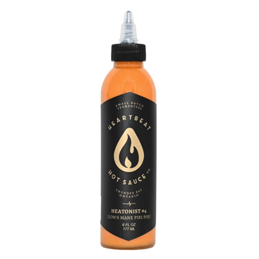 Tall squeeze bottle of Heartbeat Lion’s Mane Piri Piri Hot Sauce with black label and gold flame icon; orange sauce visible; labeled “Lion’s Mane Piri Piri” with 6 fl oz / 177 mL at the base.