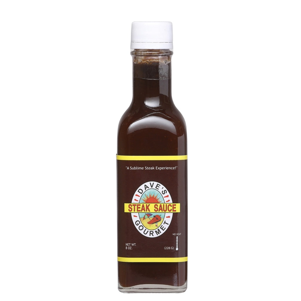 A rectangular 8-oz glass bottle of Dave’s Gourmet Steak Sauce filled with dark brown sauce. The label is deep brown with yellow borders and features the Dave’s Gourmet logo with “STEAK SAUCE” in red text. The bottle has a white cap and shows “NET WT. 8 OZ (228 g)” near the bottom. UPC: 753469000684