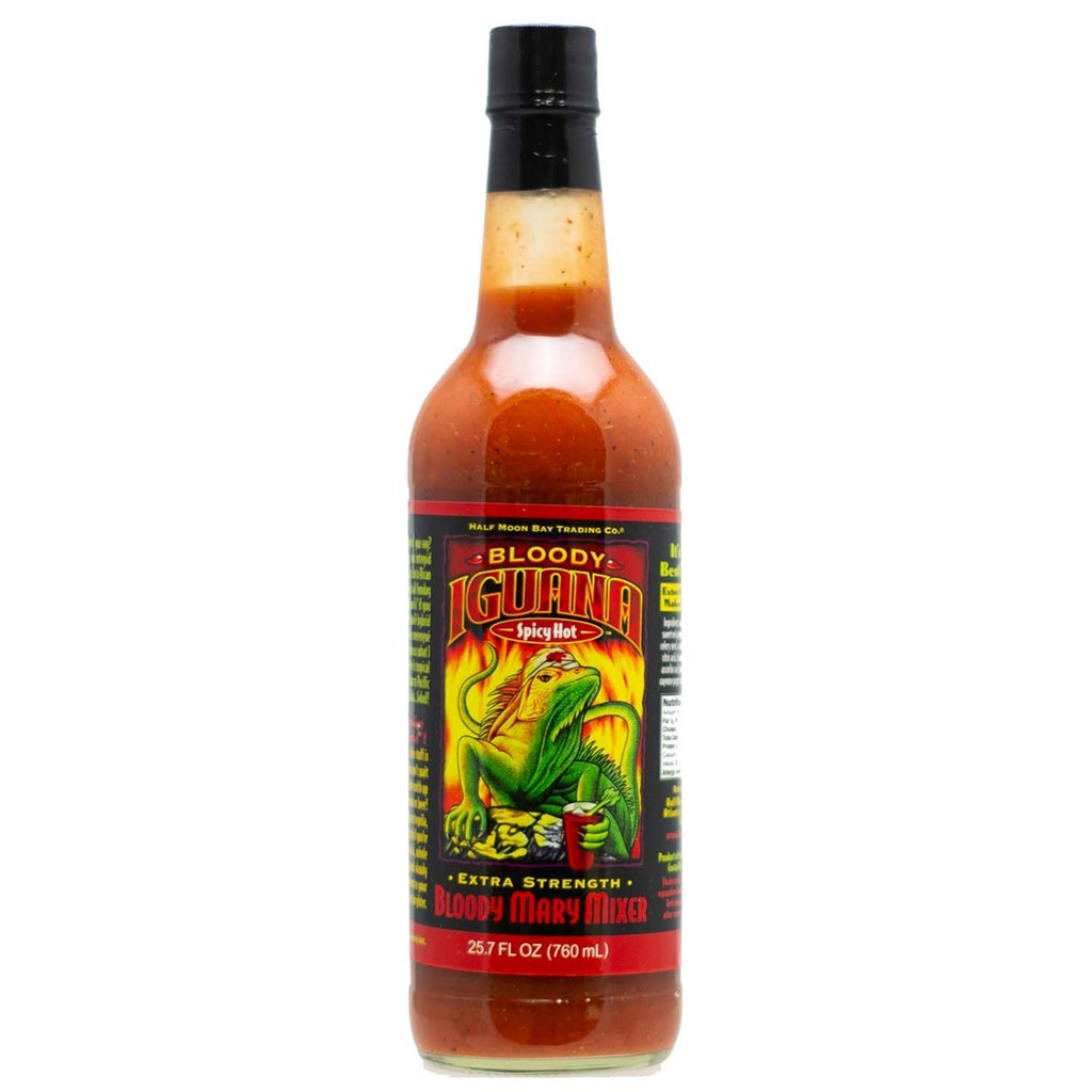 Image of a tall bottle labeled “Bloody Iguana Spicy Hot Extra Strength Bloody Mary Mixer.” The bottle contains a thick red Bloody Mary mix with visible spices. Label artwork features a green iguana holding a drink against flames. Volume shown as 25.7 fl oz (760 mL). UPC: 751059900192.