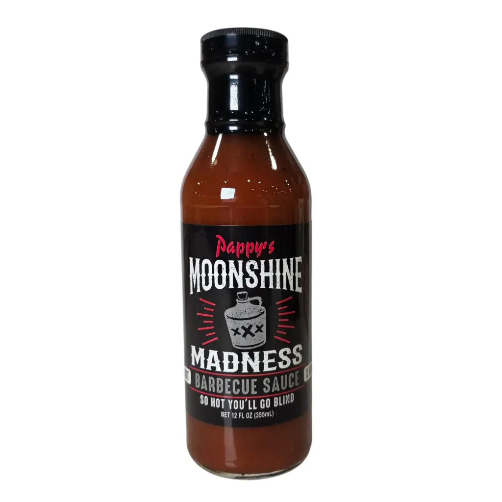 A bottle of Pappy’s Moonshine Madness Barbecue Sauce. The sauce is dark reddish-brown and comes in a 12 fl oz bottle with a black cap. The label is black with bold white and red lettering, featuring a moonshine jug marked “XXX” in the center. Text on the label reads “Pappy’s Moonshine Madness Barbecue Sauce” and “So Hot You’ll Go Blind,” emphasizing the extreme heat level.