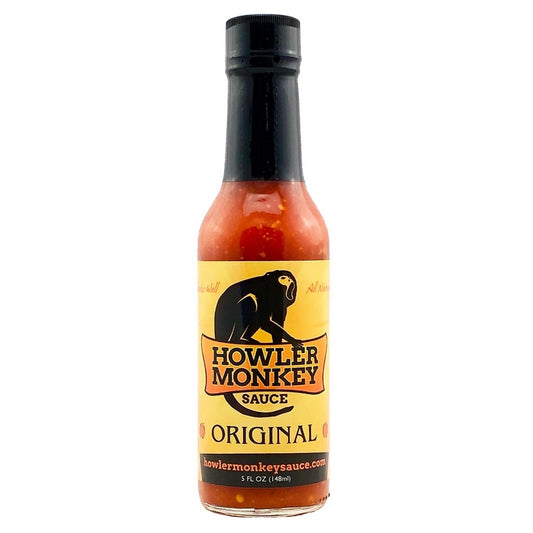A 5-ounce bottle of Howler Monkey Original Hot Sauce with a yellow label, black cap, and a black howler monkey graphic. The label features bold orange and black lettering and showcases the sauce’s bright red, pepper-speckled appearance through the glass.