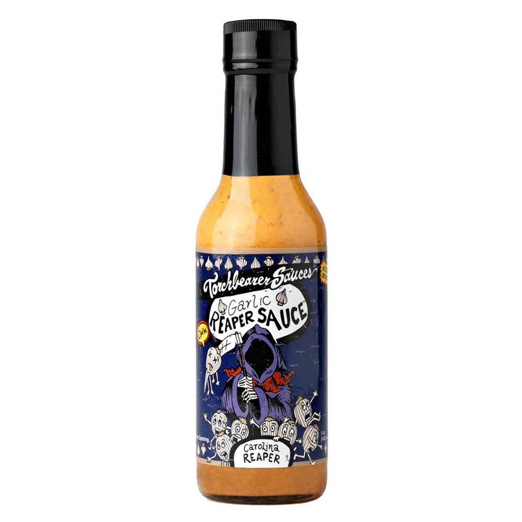 A bottle of Torchbearer Garlic Reaper Sauce with a black cap and orange-colored sauce inside. The label features a dark blue background with a cartoon reaper holding a garlic bulb, surrounded by small illustrated peppers and bold hand-drawn text reading “Garlic Reaper Sauce” and “Carolina Reaper.”