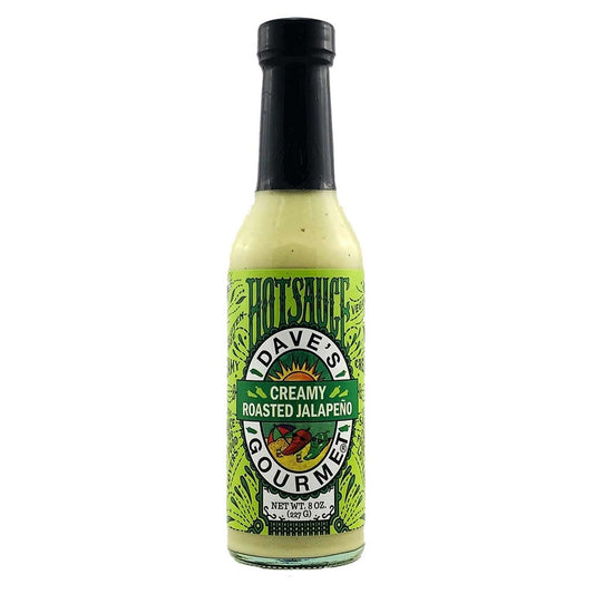 A tall 8-oz glass bottle of Dave’s Gourmet Creamy Roasted Jalapeño Hot Sauce with a bright lime-green label featuring stylized artwork and the Dave’s Gourmet emblem. The sauce inside is pale green and creamy, indicating its roasted jalapeño and tomatillo base. UPC: 753469090012
