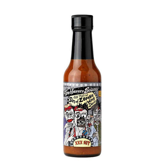 A bottle of Torchbearer Son of Zombie Wing Sauce with a black cap and dark reddish-brown sauce inside. The label features a cartoon group of zombies with exaggerated faces, surrounded by hand-drawn text reading “Son of Zombie Wing Sauce” and “XXX Hot.”