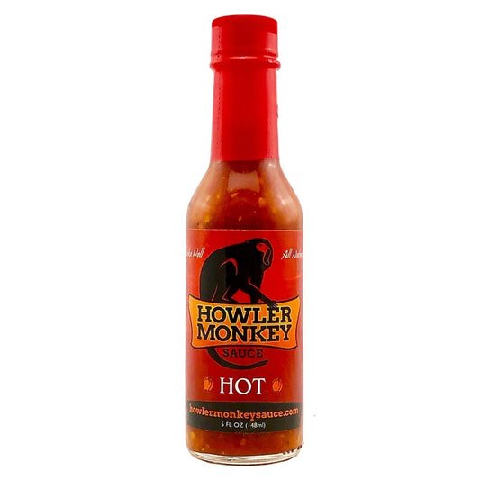 Bottle of Howler Monkey hot sauce with a red cap on a white background