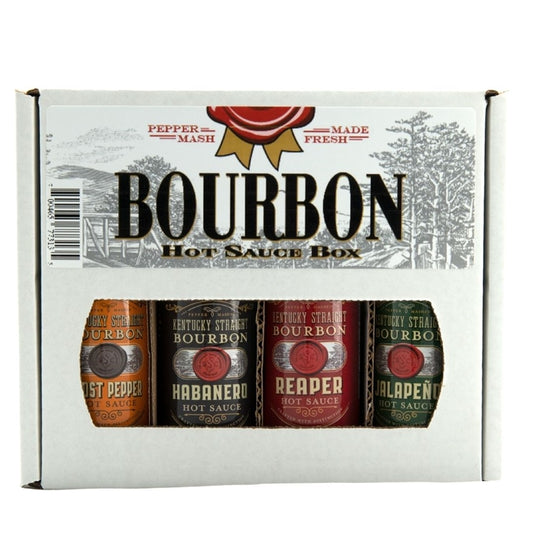 A boxed Kentucky Straight Bourbon Hot Sauce 4-pack set displayed in a white gift carton labeled “Bourbon Hot Sauce Box.” The front window shows four bottles in different flavors: Ghost Pepper (orange label), Habanero (black label), Reaper (red label), and Jalapeño (green label).