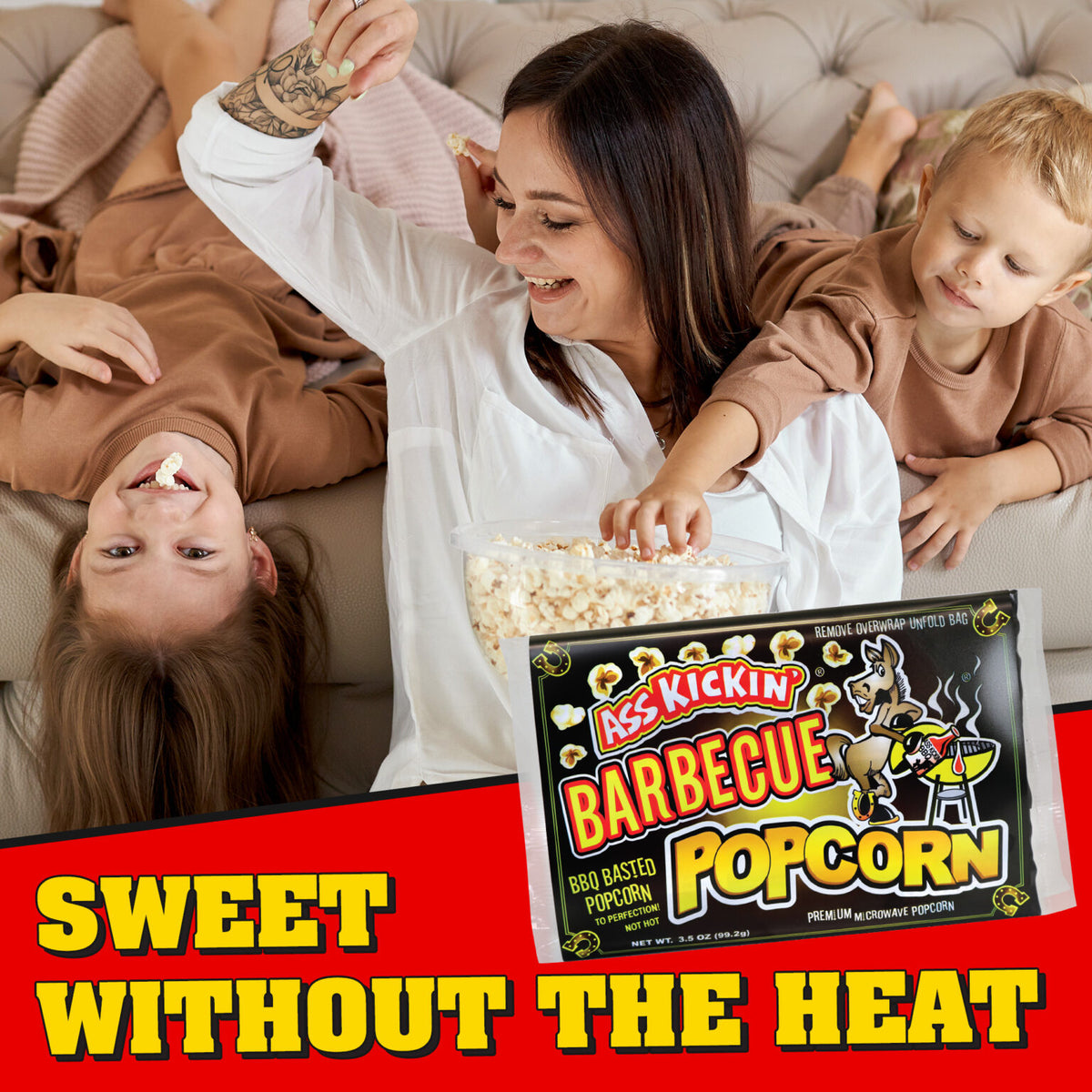 A family of three lounges on a beige couch sharing a bag of Kicks Kickin' Barbecue Popcorn. The woman in the center holds a clear bag filled with white popcorn, while a young boy in a brown sweatshirt reaches for a kernel.