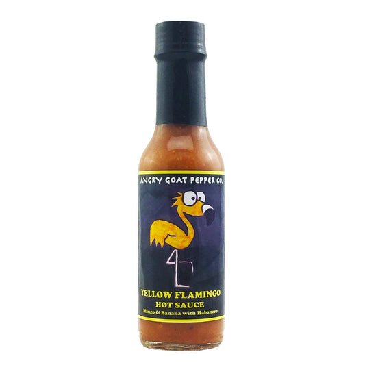 A bottle of Angry Goat Pepper Co. - Yellow Flamingo Hot Sauce, featuring a vibrant and tropical label design with a yellow flamingo in the center. The sauce's name is displayed, along with a description emphasizing its citrusy kick and tropical flavors. The heat level is mentioned as 4 out of 10. The ingredients are listed with emoji representations of mango, chili pepper, and banana. The UPC code is 706795003744