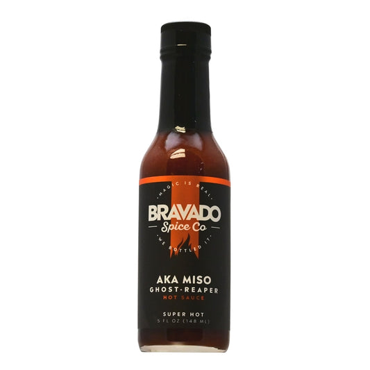 Bottle of Bravado Spice Co. Aka Miso Ghost Reaper Hot Sauce, featuring a fiery design and vibrant label. The bottle is filled with a dark brownish-red hot sauce, promising a thrilling flavor experience. The brand logo is prominently displayed, conveying boldness and excitement. The sauce is surrounded by chili peppers and other ingredients, representing the intense and flavorful blend. The bottle size is 5 oz, and the UPC is 850771005311.