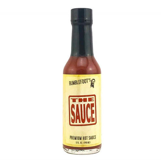 A bottle of Bumblefoot's The Sauce Hot Sauce, featuring a clean and elegant label design. The sauce's name is displayed prominently. The description emphasizes the sauce's versatility and award-winning nature. The ingredients are listed, and the heat level is described as mild. The UPC code 653581300016