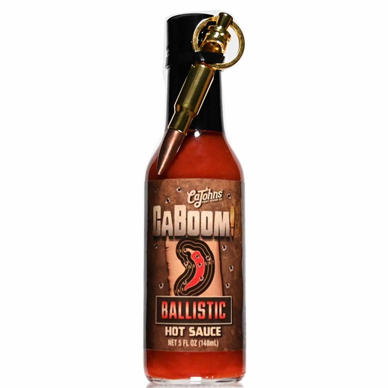 A bottle of Caboom! Ballistic Hot Sauce with a bullet bottle opener keychain attached. The label features an illustration of a bullet and the text "Caboom! Ballistic Hot Sauce: Unleash the explosive flavor! UPC: 647293010158