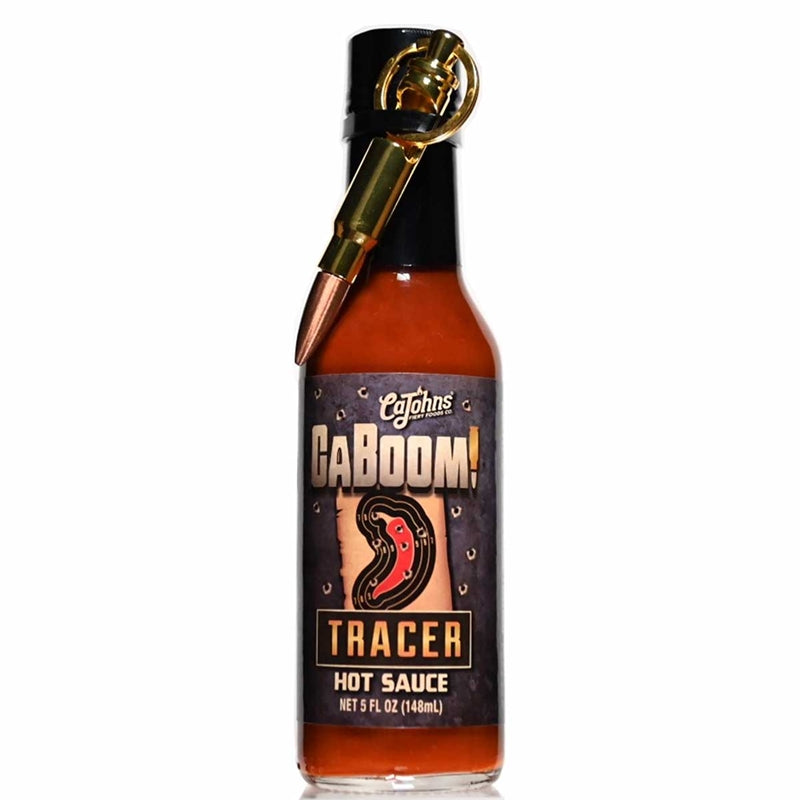 A bottle of Caboom! Tracer Hot Sauce with a bullet bottle opener keychain attached. The label features an illustration of a bullet and the text Caboom! Tracer Hot Sauce: Prepare to have your taste buds blown away! UPC: 647293010165.