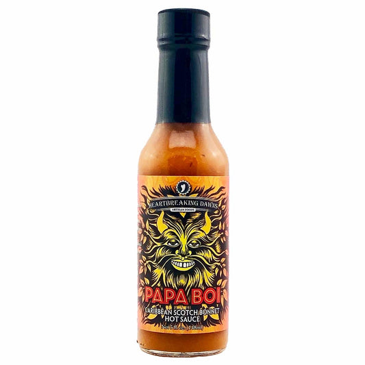 A bottle of Heartbreaking Dawn's Papa Boi Caribbean Scotch Bonnet Sauce, featuring a vibrant label with chili pepper imagery and the text 'Elevate Your Meals to Caribbean Bliss with Papa Boi Scotch Bonnet Sauce!' The background suggests a tropical beach scene, evoking the flavors of the Caribbean. UPC: 683720300706.